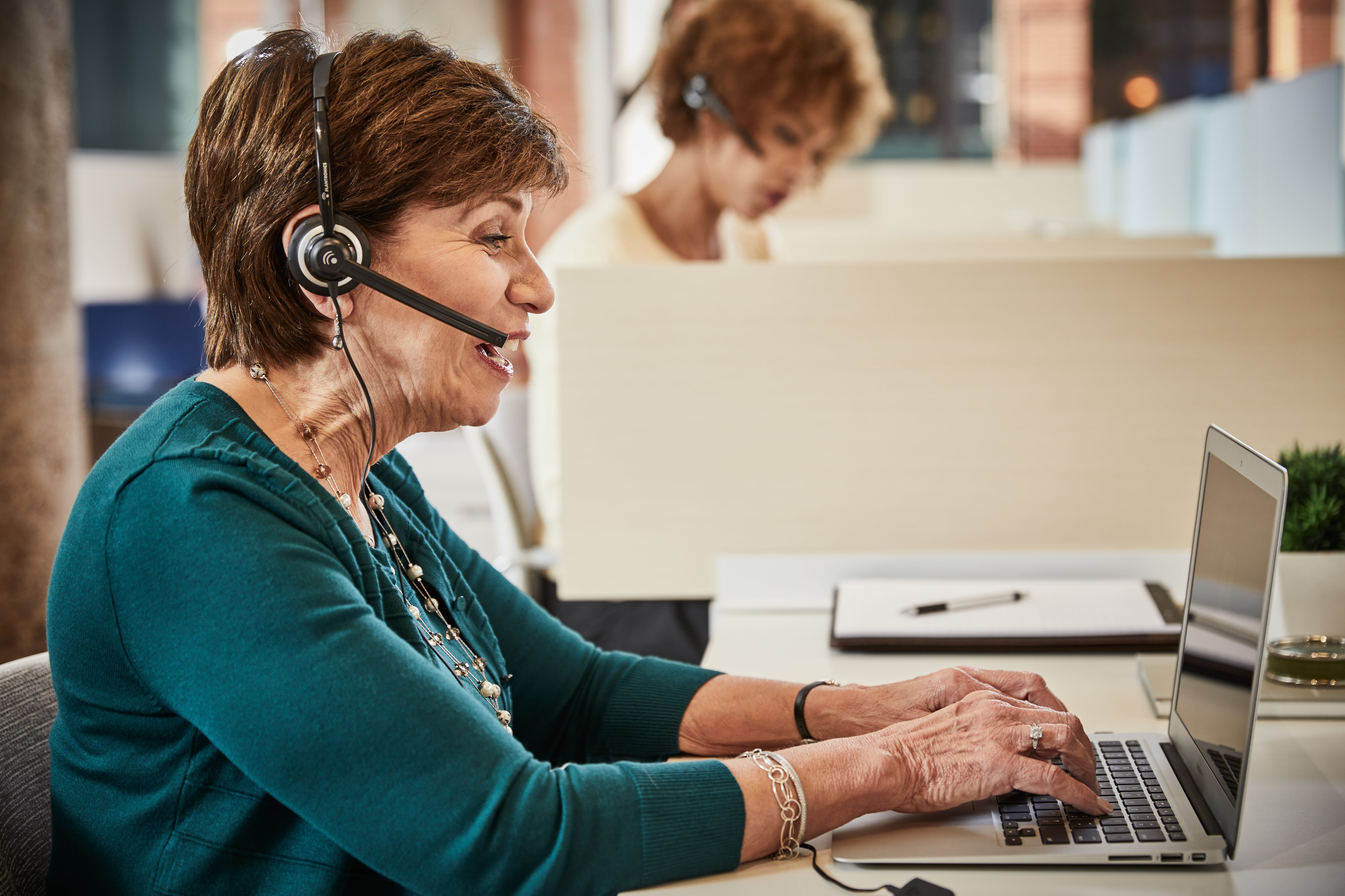 Associate working on a laptop and talking on a headset