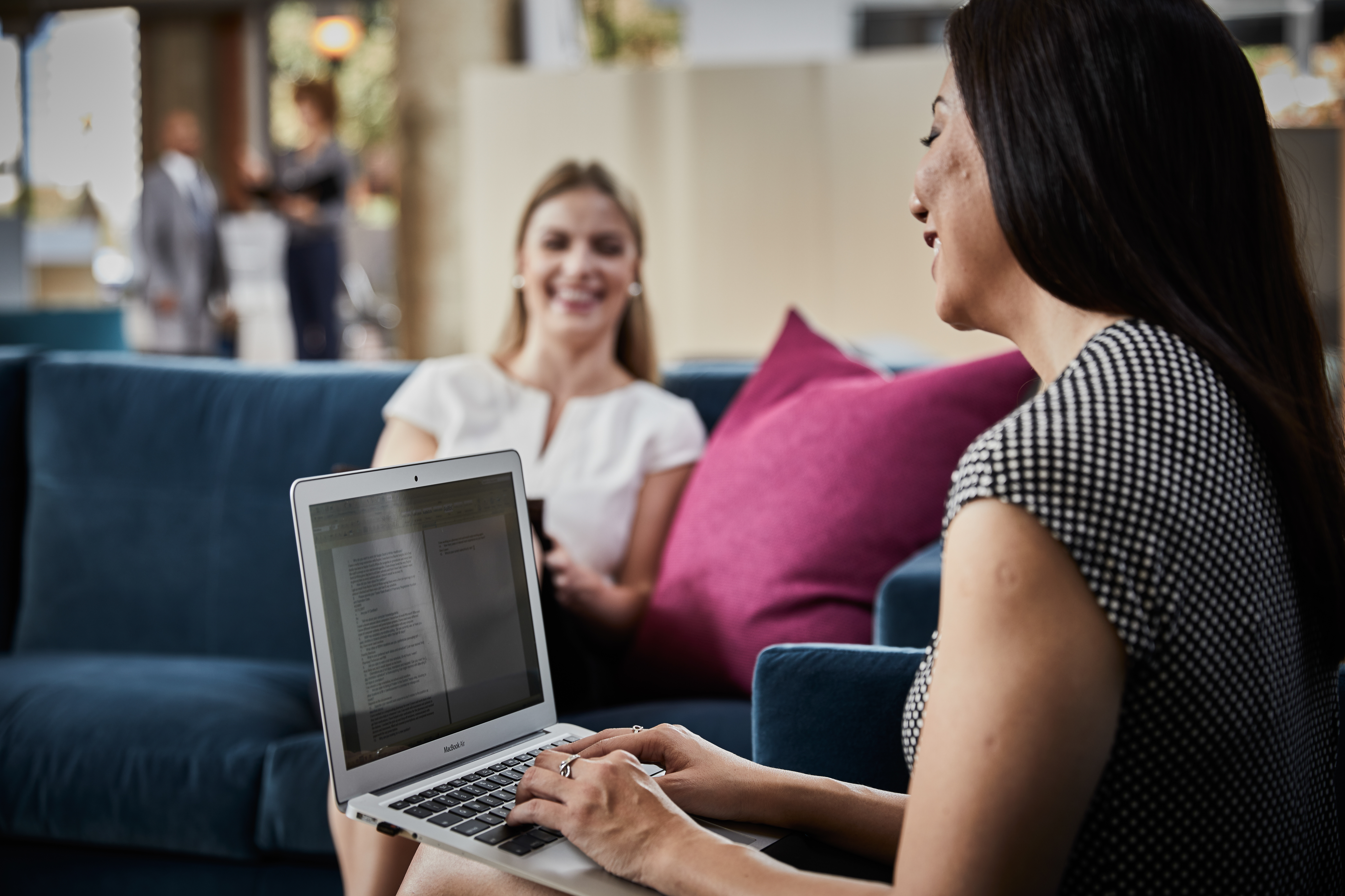 Associate works on laptop while having a conversation with another associate