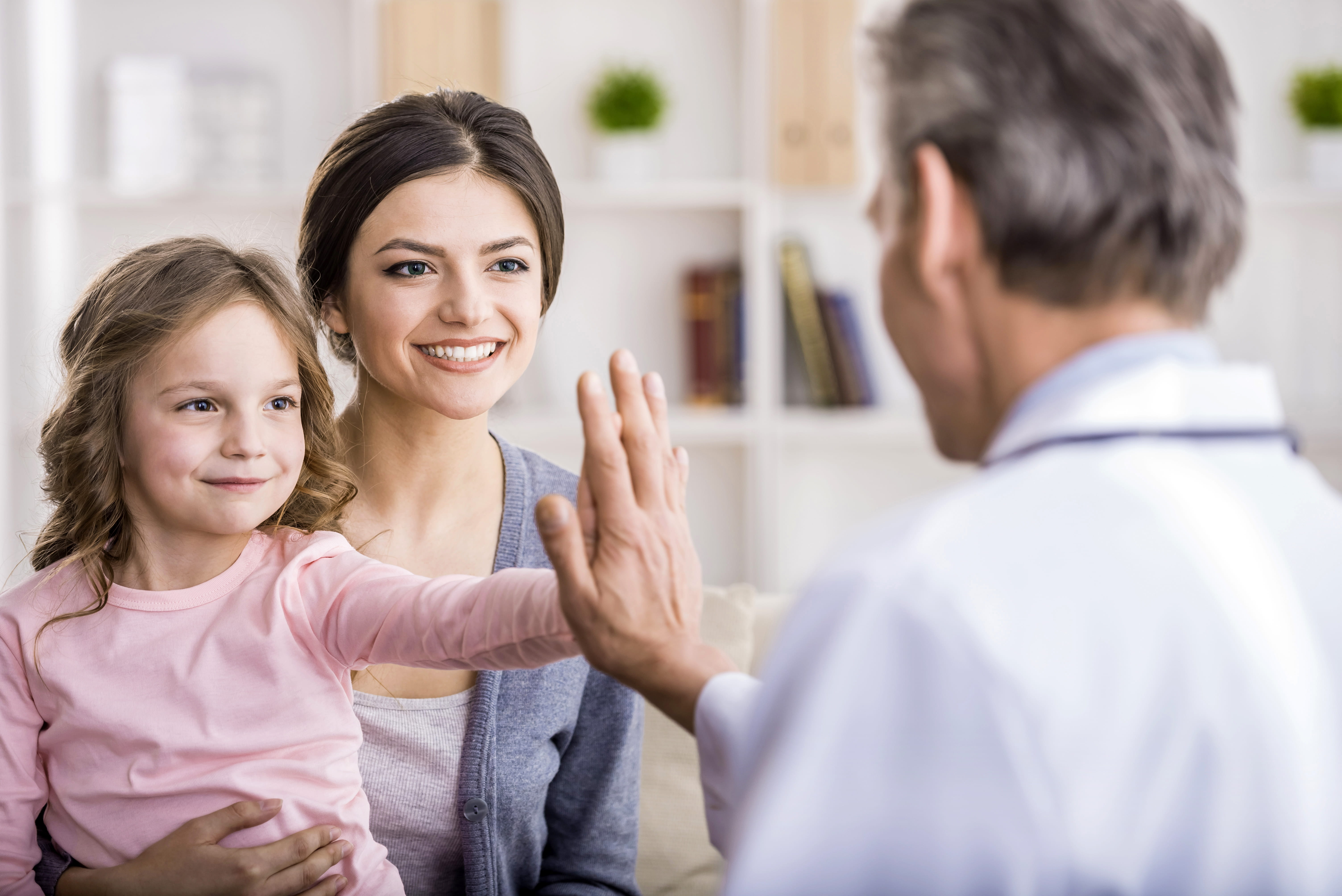 Mother and daughter high-five a healthcare provider